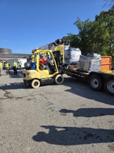Forklift unloading electrical storm recovery supplies at a staging area